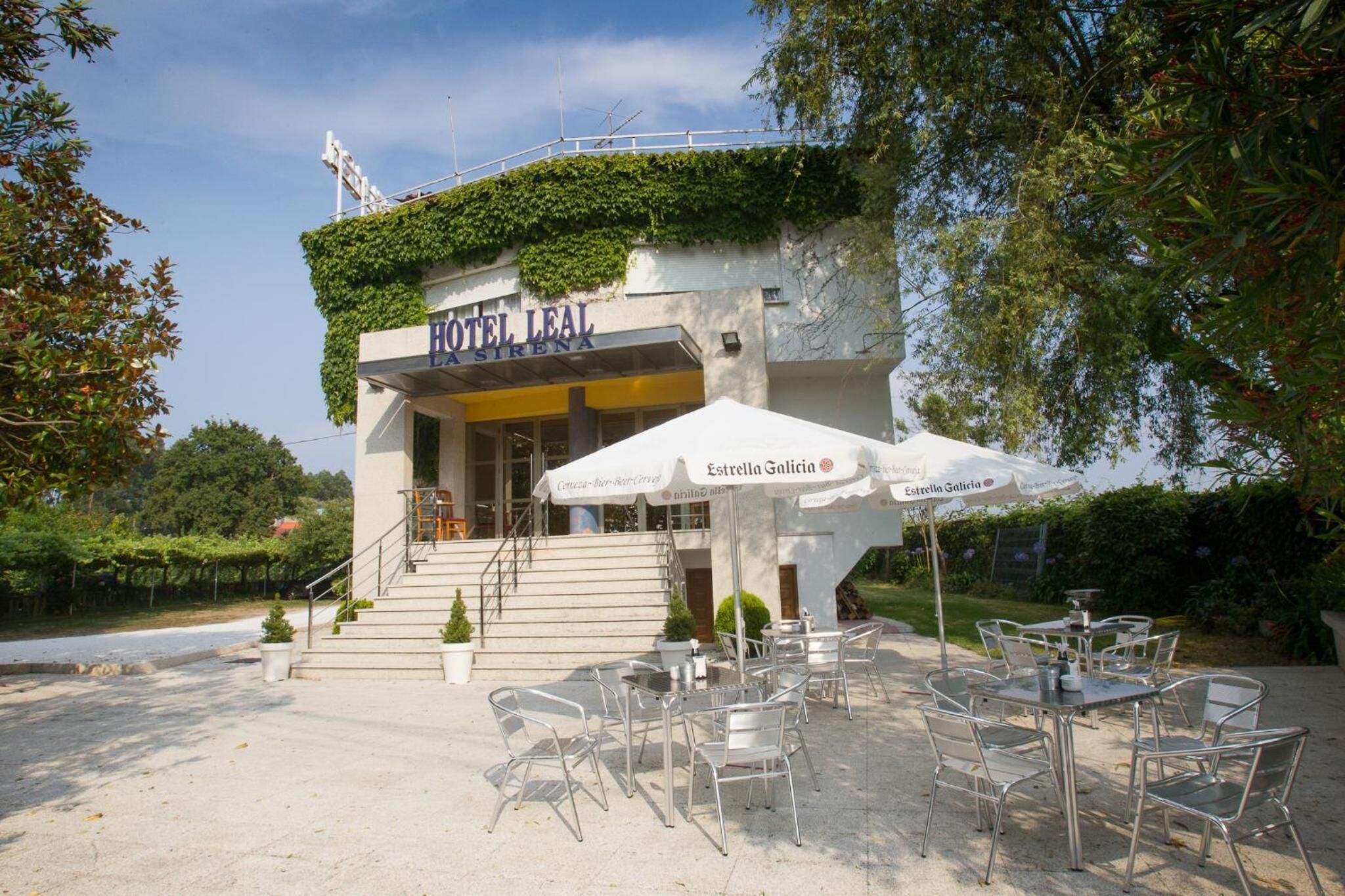 A hotel named "HOTEL LEAL" with outdoor seating and a staircase leading to the entrance.