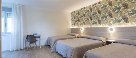 Habitación de hotel con tres camas, un escritorio y una silla.