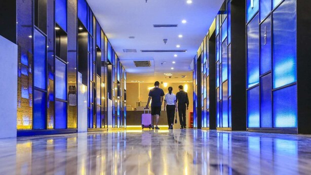 A hotel corridor with reflective floors and blue-tinted glass panels. - 9H Hotel (Chongqing)