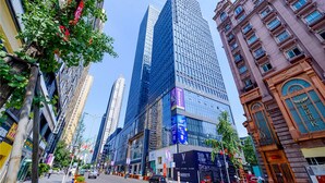 A city street lined with tall buildings, including a modern skyscraper and a historic building with ornate details. - 9H Hotel (Chongqing)