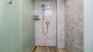 A modern bathroom with a glass shower enclosure, marble tiles, and a wooden floor. - 9H Hotel (Chongqing)