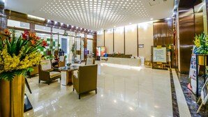 Un moderno vestíbulo de hotel con mostrador de recepción, zona de estar y una decoración floral.