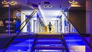 A modern hotel interior with a central staircase, glass railings, and a person walking down the stairs. - 9H Hotel (Chongqing)