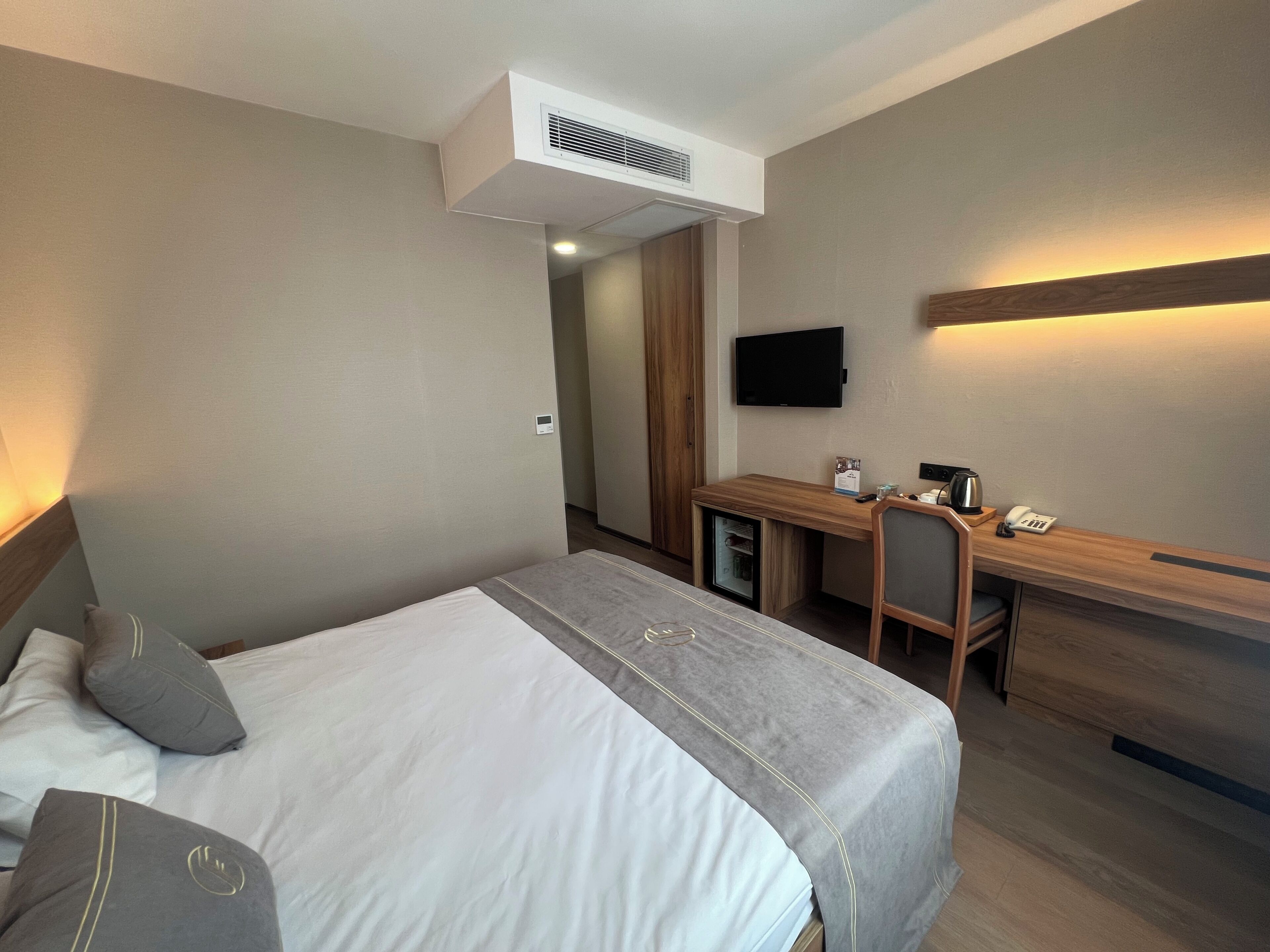 Una habitación de hotel con cama, escritorio, silla, televisor y minibar.