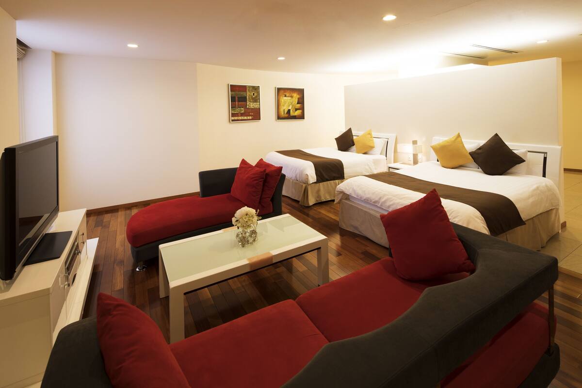 A hotel room with a sofa, a bed, a TV, and a coffee table.