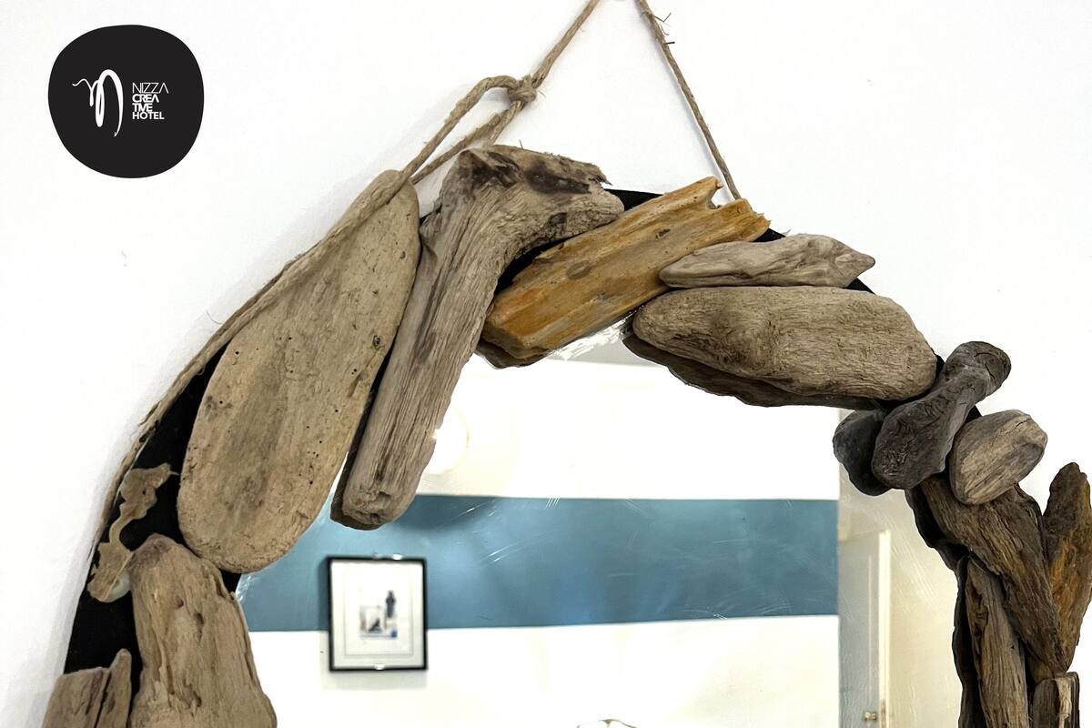 Un espejo de madera rústica con acabado natural, fijado a una pared blanca.