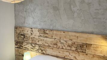 Un dormitorio con pared de hormigón, cabecero de madera y una lámpara de noche.