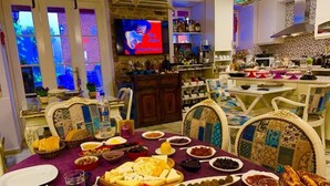 A dining area with a purple tablecloth, various dishes, and a television in the background. - Lusin Butik Hotel (Ayvalik)