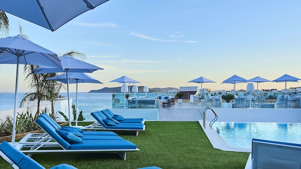 A poolside area with lounge chairs and umbrellas, a pool, and a view of the sea. - Eurostars Ibiza (Ibiza Town)