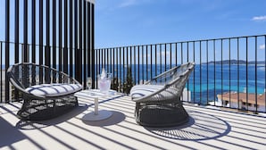 A balcony with two wicker chairs and a table, overlooking a coastal view. - Eurostars Ibiza (Ibiza Town)