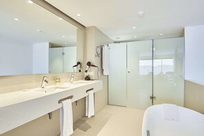 Un baño moderno con un espejo grande, dos lavabos, una ducha y una bañera.