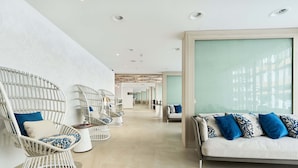 A modern hotel lobby with wicker chairs, a sofa, and a large window. - Eurostars Ibiza (Ibiza Town)