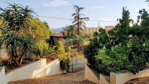 A residential area with a gated entrance, lush greenery, and a building with a red roof in the background. - 800 at Merton (Pretoria)