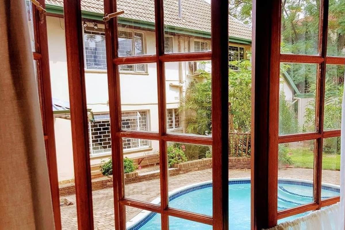 Une vue à travers une fenêtre, avec une piscine visible à l'extérieur.