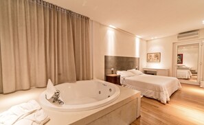 A modern hotel room with a large bathtub, a bed, a desk, and a mirror. - Hotel Radice (Civitanova Marche)