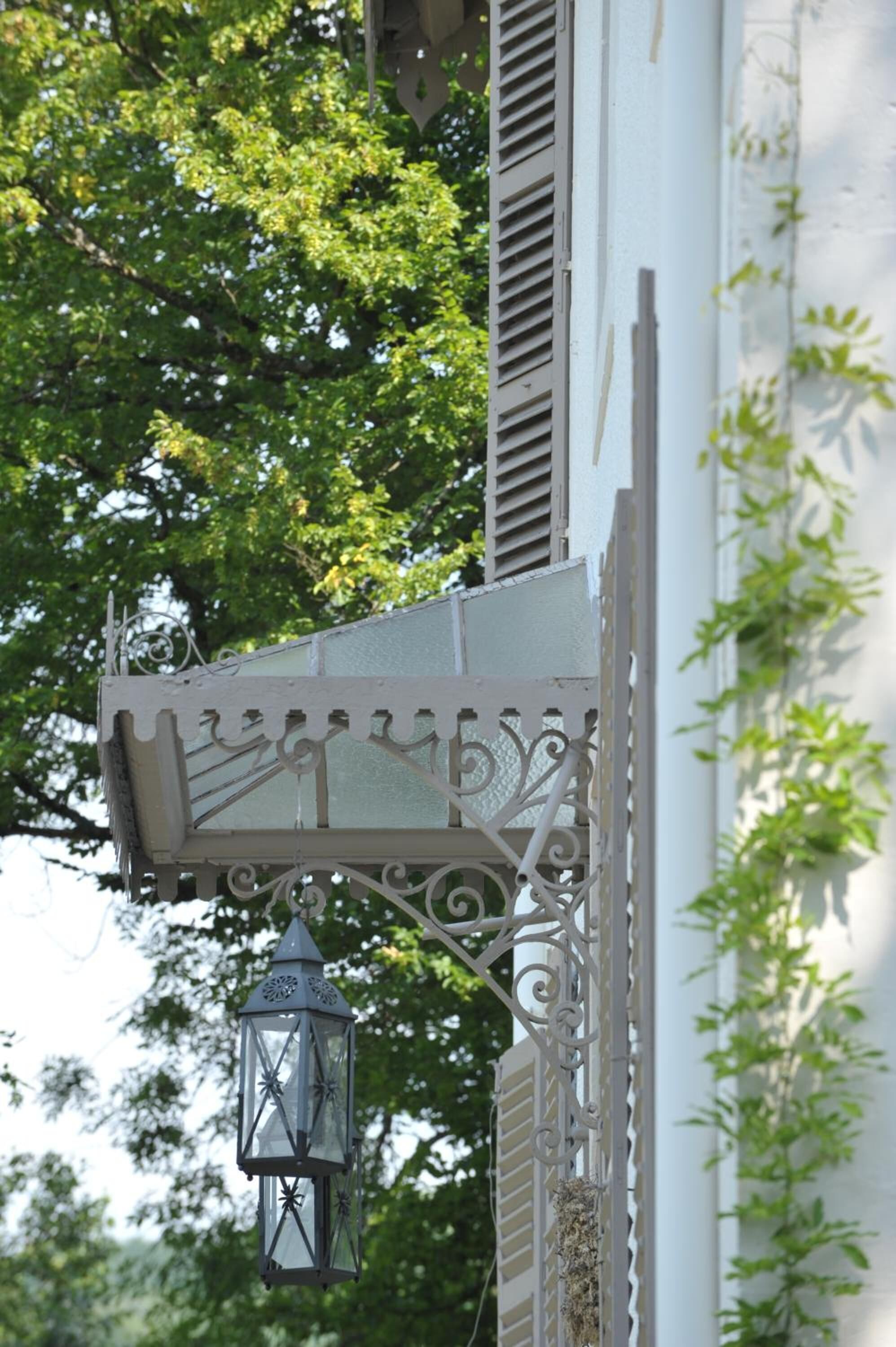 Un bâtiment blanc orné d’une lanterne en métal décorative suspendue à un balcon.