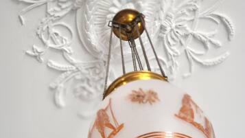 A hanging light fixture with a white and orange design, featuring a central brass element and decorative patterns.