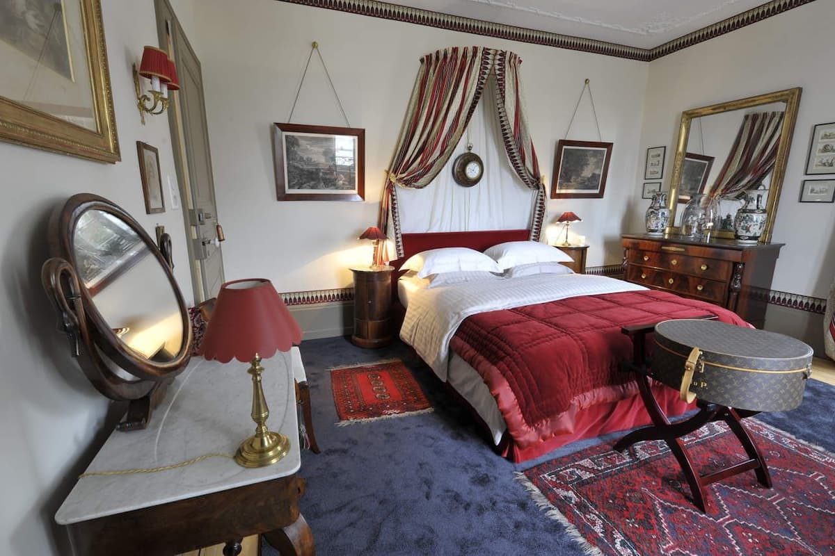 A bedroom with a bed, a dresser, a mirror, and a small round table.