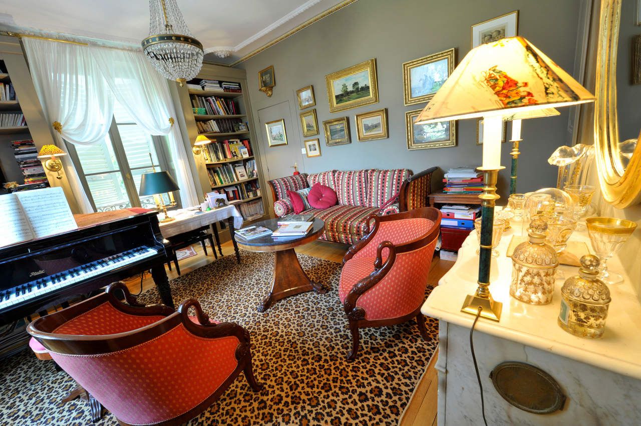 A living room with a grand piano, a sofa, a coffee table, and a patterned carpet.