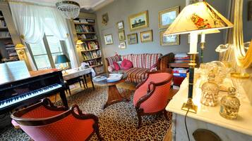 A living room with a grand piano, a sofa, a coffee table, and a patterned carpet.
