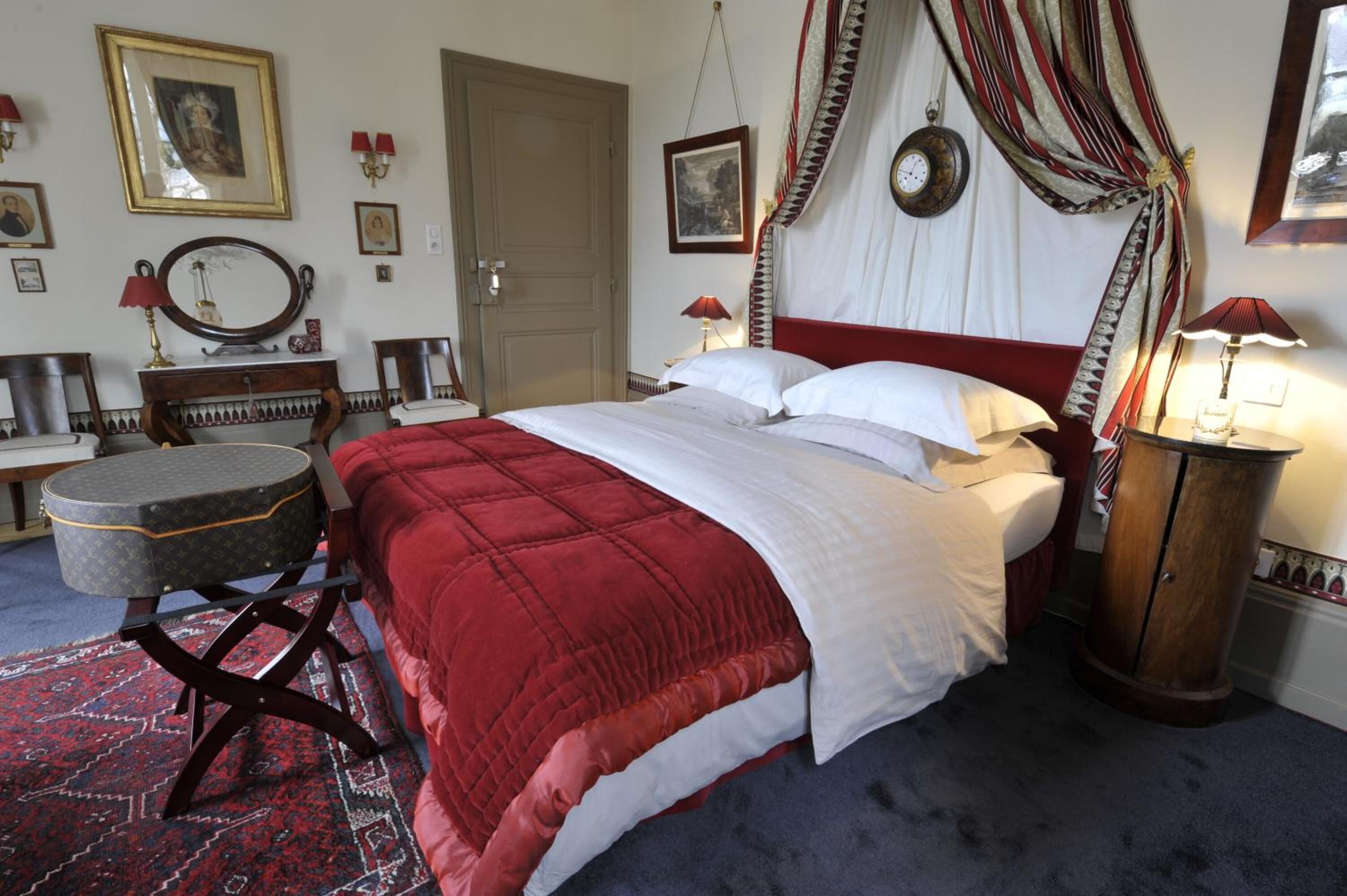 Une chambre à coucher avec un grand lit, une table de chevet, un miroir et une armoire.