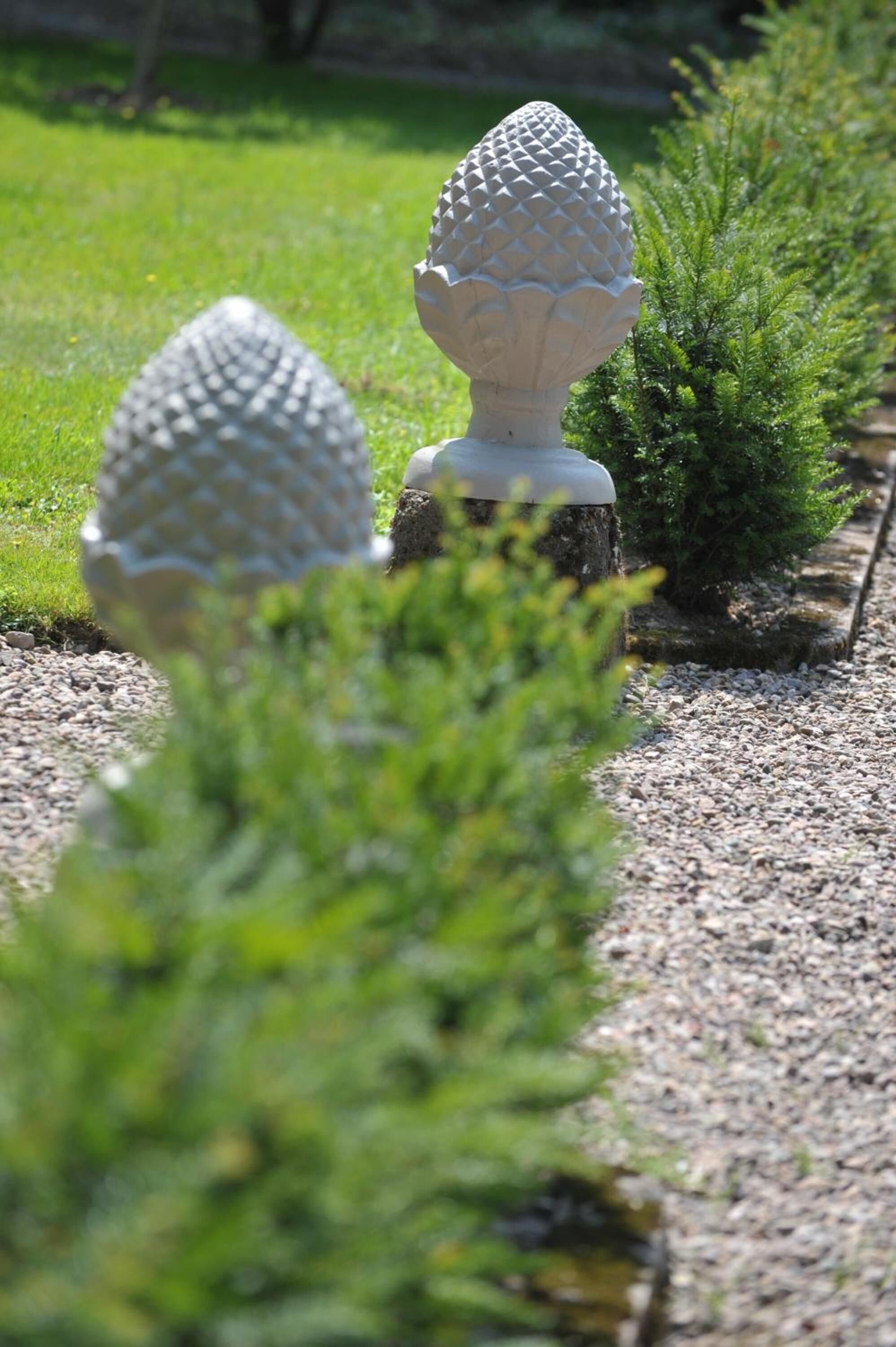 Un jardin agrémenté de deux sculptures sphériques en pierre, le long d’un chemin de gravier.