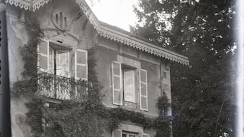 Un edificio de dos pisos con un balcón, ventanas grandes y una chimenea.