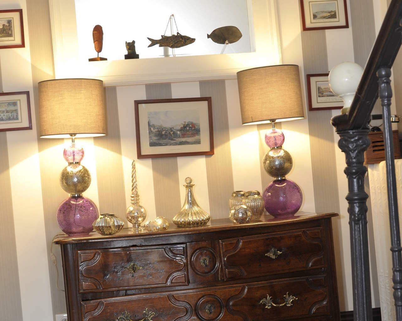 Une commode en bois, agrémentée de lampes décoratives et surmontée d’un tableau encadré.