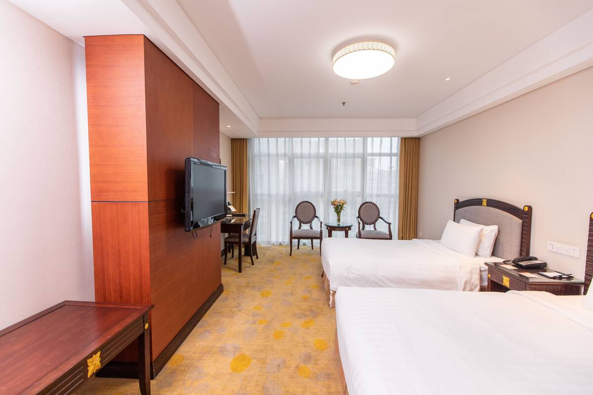 Une chambre d’hôtel avec deux lits, une télévision, un bureau et une chaise.