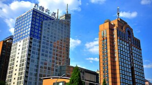 A modern high-rise building with a glass facade and a traditional red brick building with a curved facade. - Beijing Broadcasting Tower Hotel (Beijing)