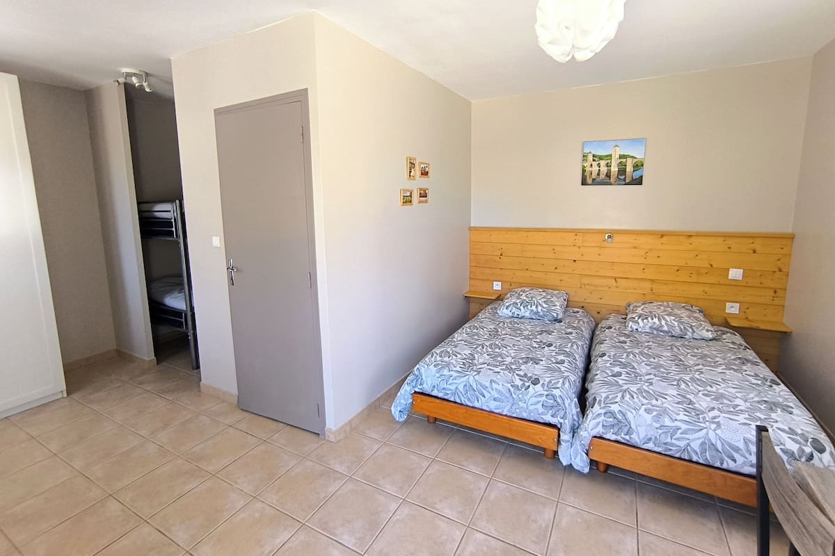 A bedroom with two beds, a wooden headboard, a door, and a small picture on the wall.