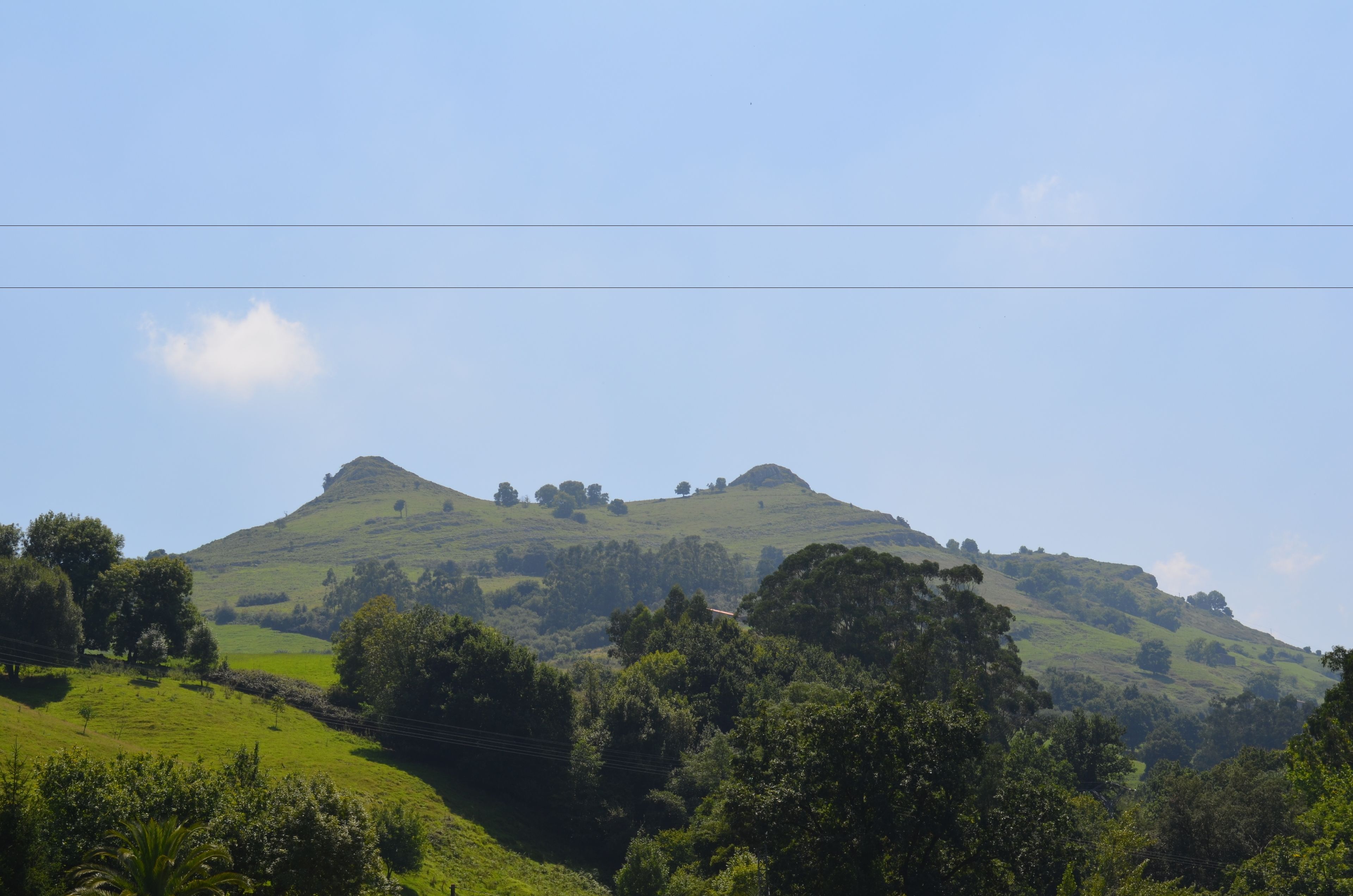 Un paisaje montañoso con una colina destacada y abundante vegetación.