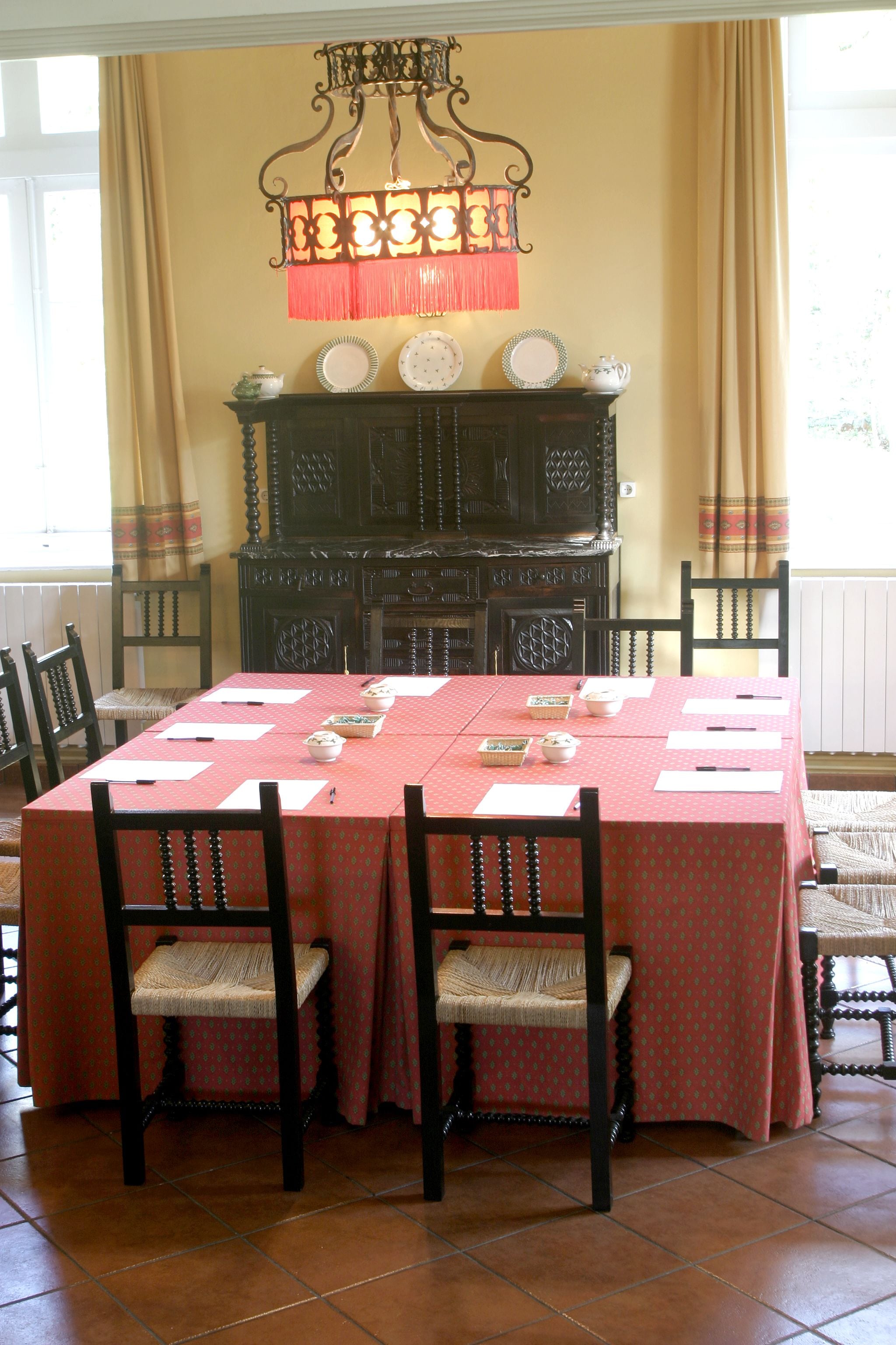Una sala menjador amb estovall daurat, caires de fusta, un penjallum i una llar de foc amb plats decoratius.