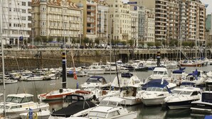 Un puerto deportivo con varias embarcaciones amarradas, rodeado de edificios de varios pisos con balcones y el letrero de un hotel.