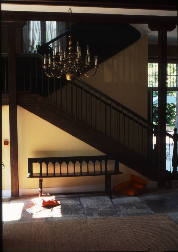 Una escalera con un candelabro, un banco y vistas al exterior.