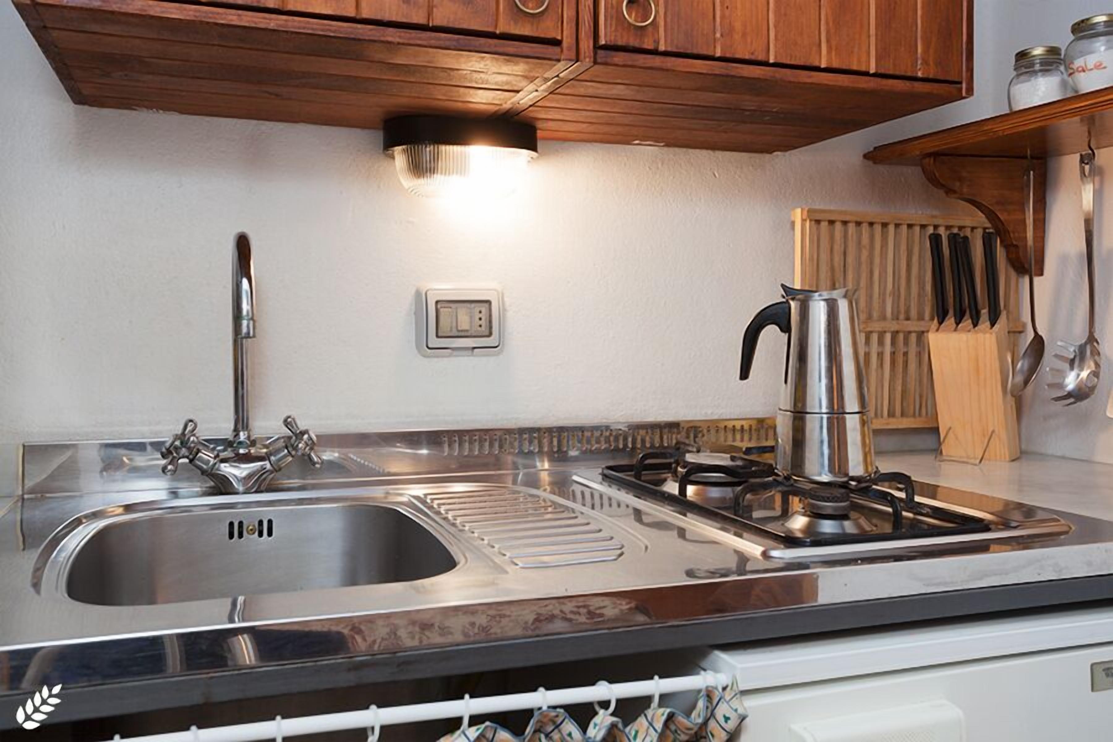 A kitchen with a stainless steel sink, a gas stove, and wooden cabinets.