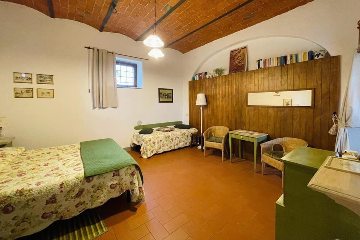 A cozy room with two beds, a wooden wall, a small table, and a window.