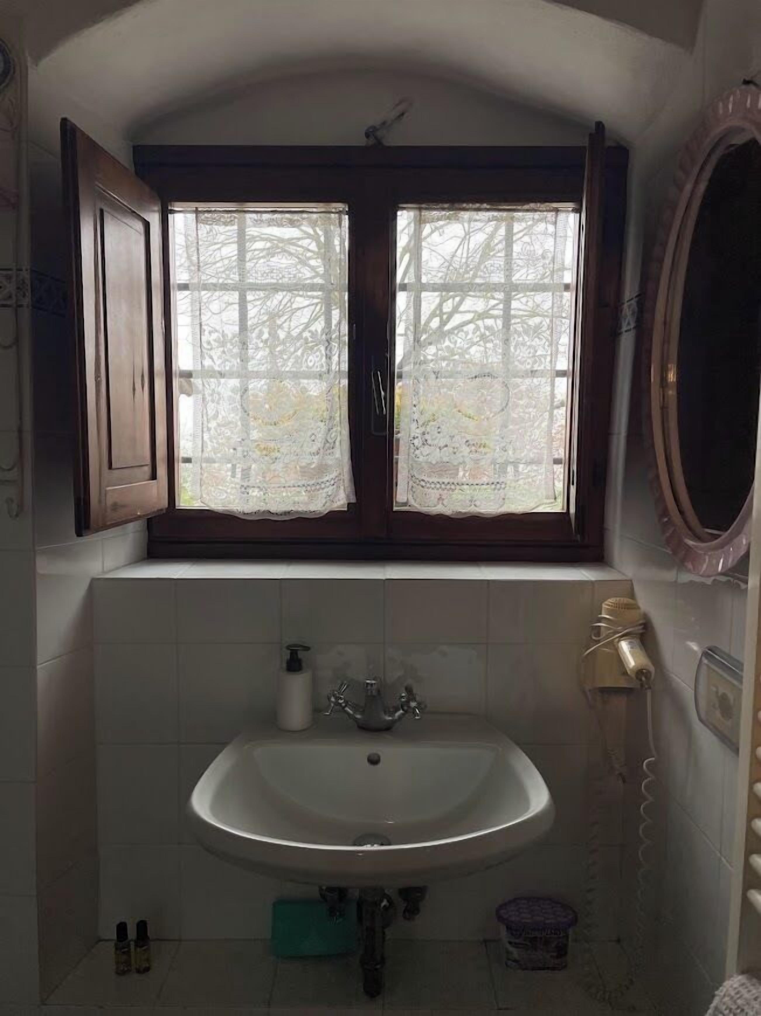 Une salle de bain avec une fenêtre, un lavabo et un miroir.