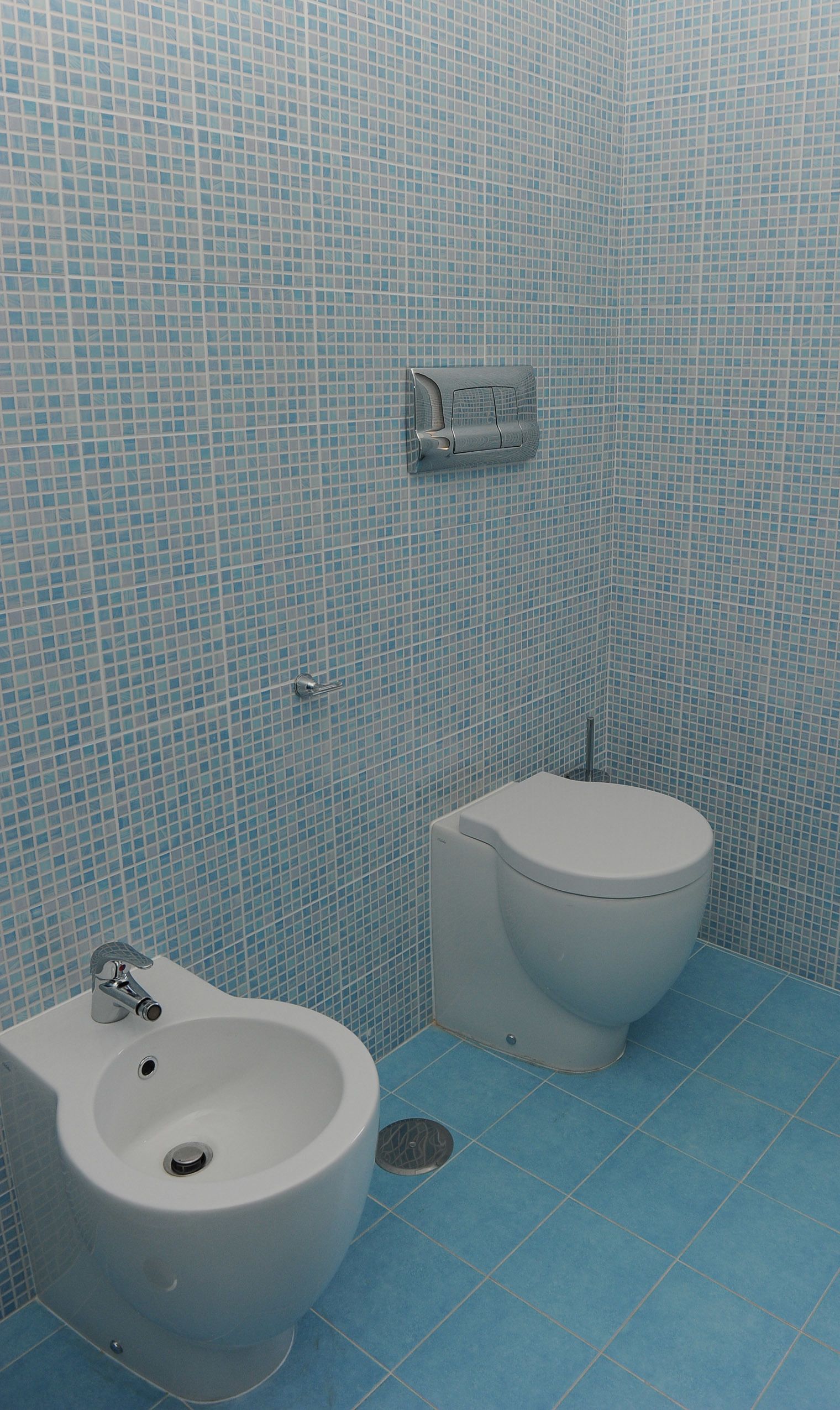 A bathroom with a bidet, toilet, and a wall-mounted faucet.