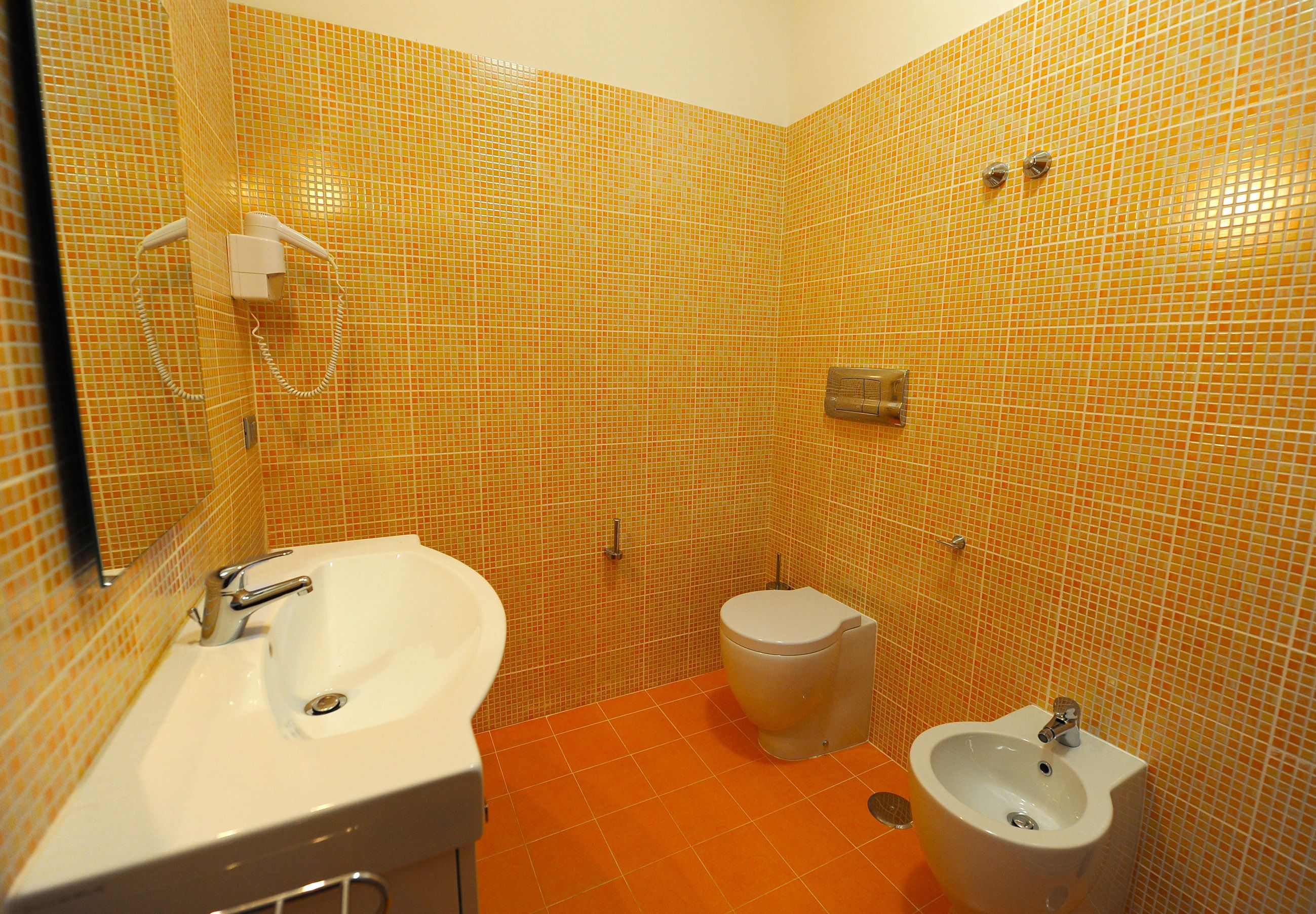 Un baño con lavamanos, inodoro, bidé y espejo.