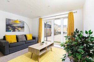 A modern living room with a sofa, coffee table, and a large window with yellow curtains.