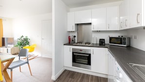 A modern kitchen with white cabinets, a built-in oven, a microwave, and a coffee maker.