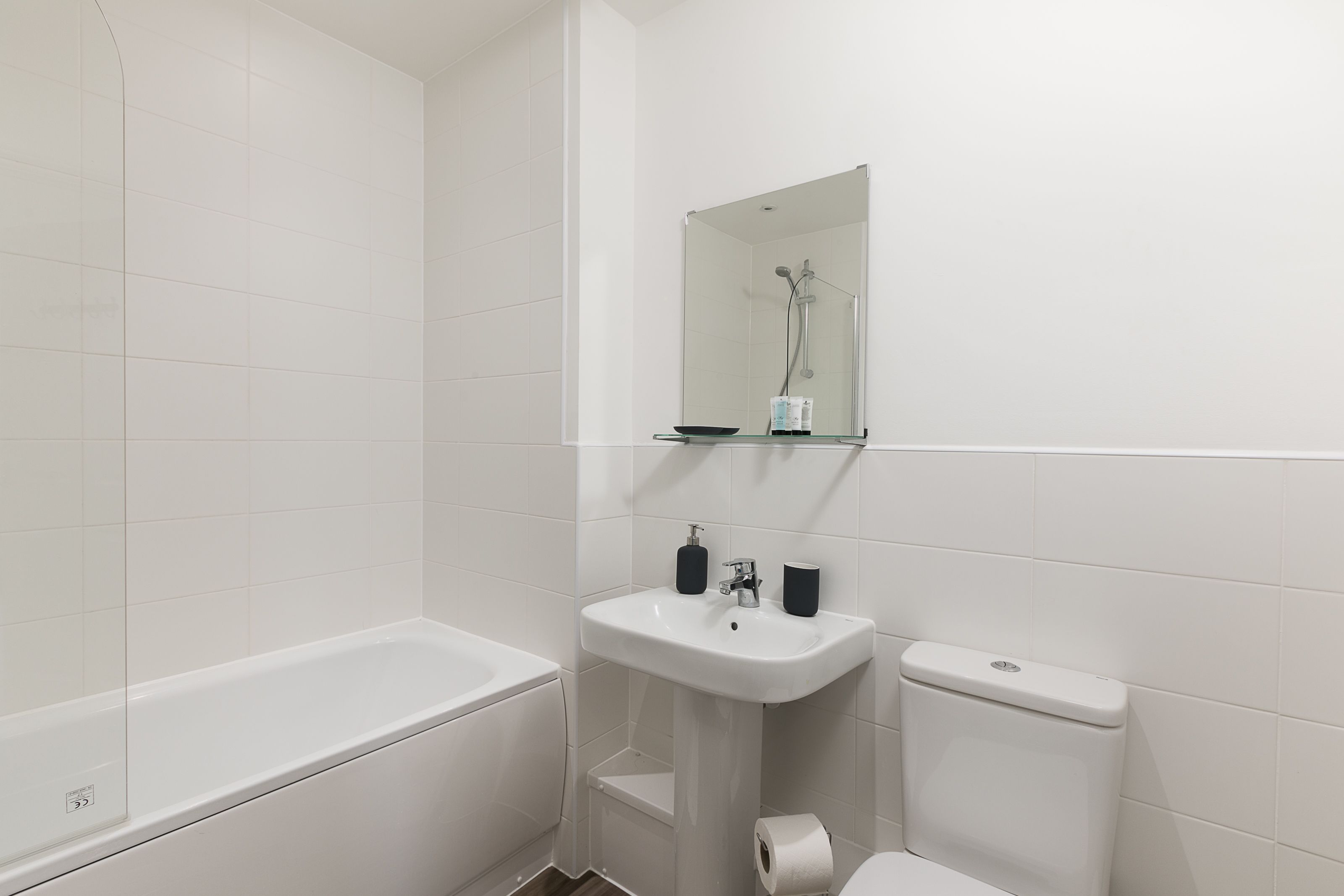 A bathroom with a bathtub, a sink, a toilet, and a mirror.