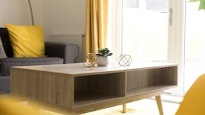 A modern living room with a wooden coffee table, a potted plant, and decorative items.