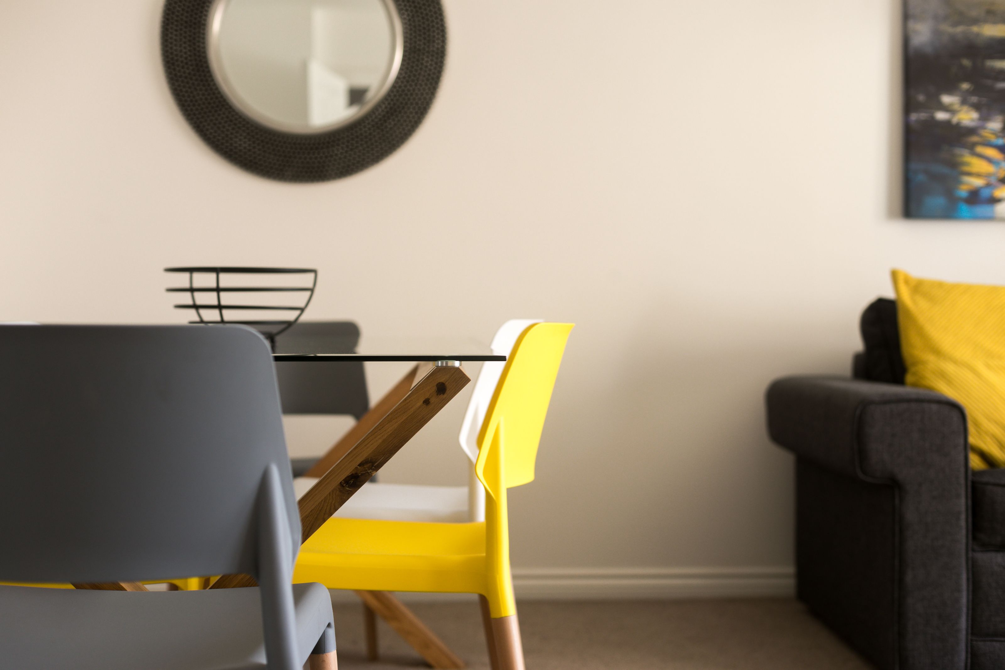A modern living room with a grey sofa, a yellow chair, and a black coffee table.