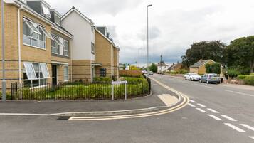 A residential street with houses, a 'MUTINY CLOSE' sign, and cars parked along the road.