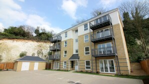 A multi-story residential building with a brick facade, balconies, and a paved driveway.
