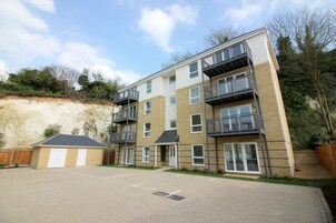 A multi-story residential building with a brick facade, balconies, and a paved driveway.