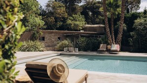A pool area with lounge chairs and a stone building in the background. - La Villa d'Andrea (Ramatuelle)