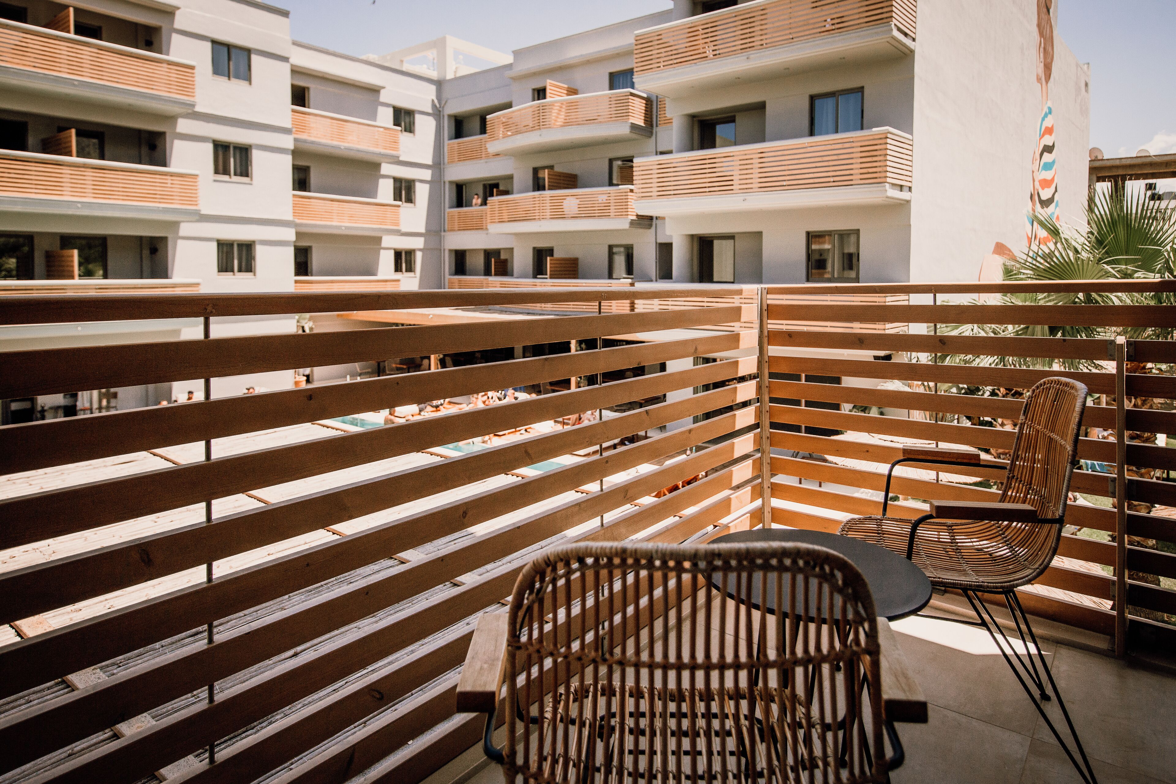 Un balcon avec des lattes en bois, une chaise en osier et une table.